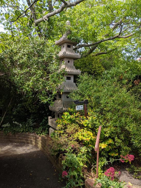 A carved pink granite six tier pagoda garden lantern, Height 10ft